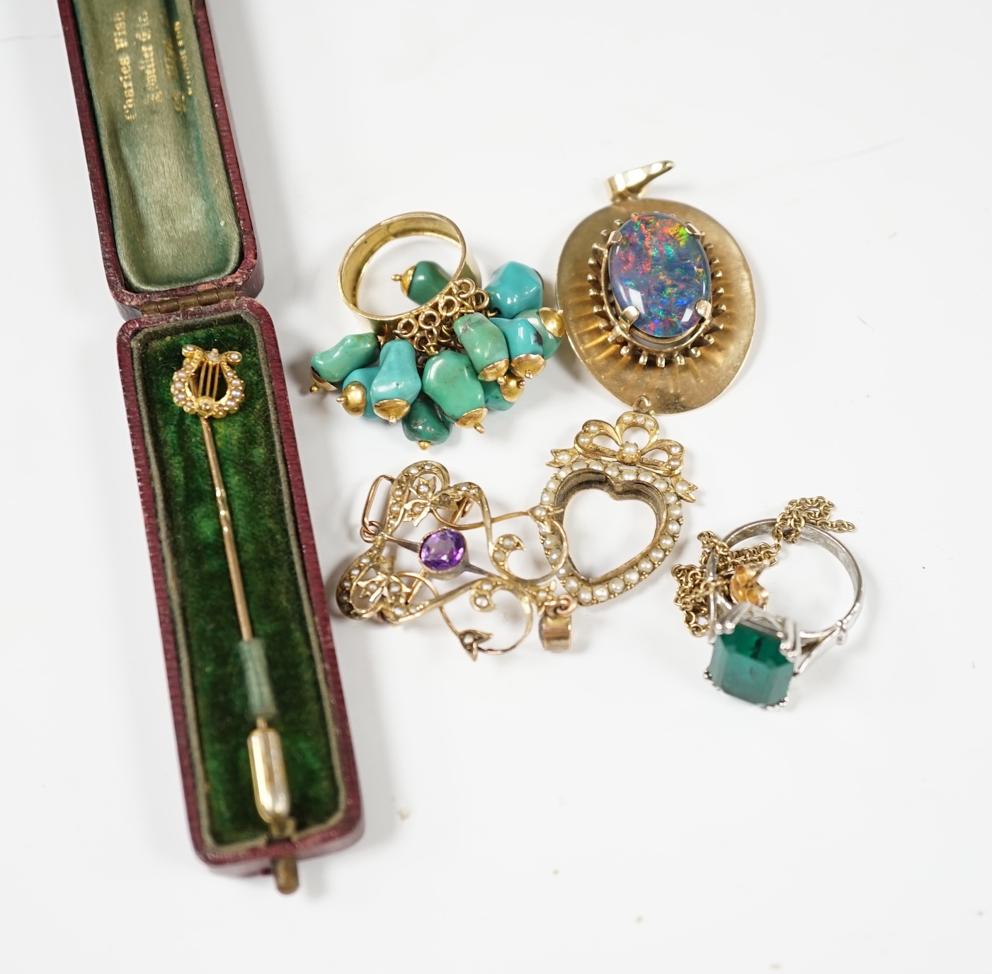 A group of jewellery including a yellow metal and seed pearl set stick pin, with lyre terminal and a 9ct and gem set pendant. Condition - poor to fair